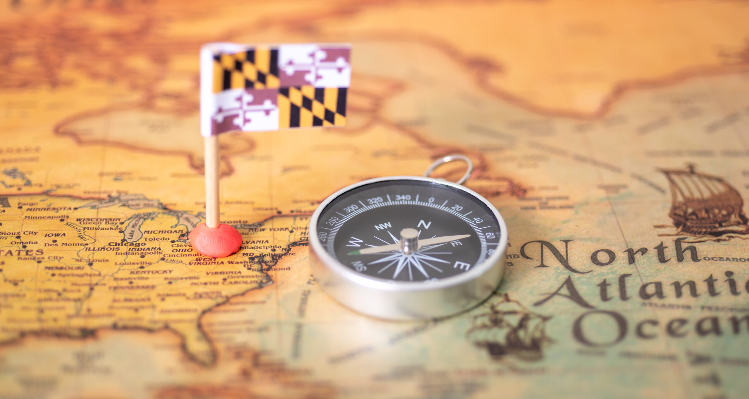The flag of Maryland and the compass on the old world map. The concept of domestic tourism and recreation in America.