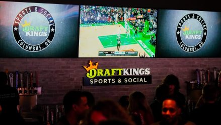 Sports are shown on TVs behind a bar as guests enjoy the grand opening of DraftKings Sports & Social in Ohio.