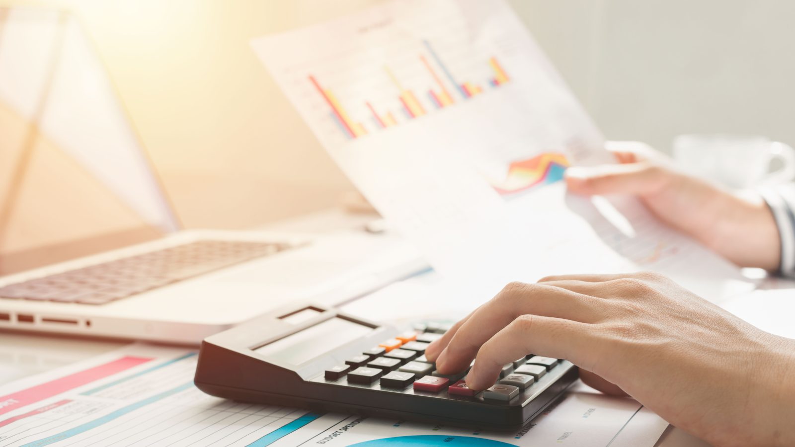 Business woman using calculator and writing make note with calculate. taxes and economic concepts. Savings, finances and economy concept through a laptop.