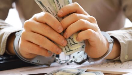hands-handcuffed-$100-bills